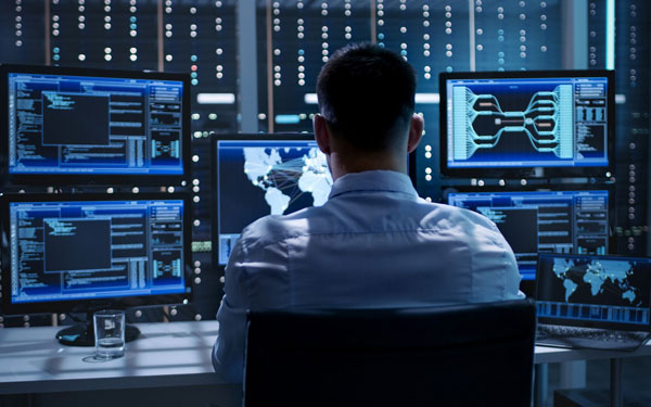 man sitting in front of multiple security screens