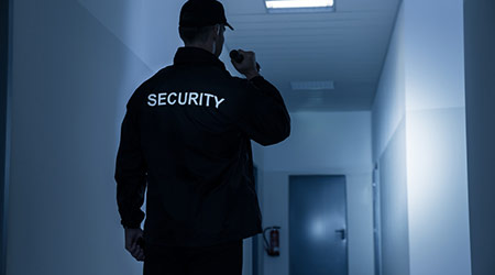 security guard shining a flashlight down a hall